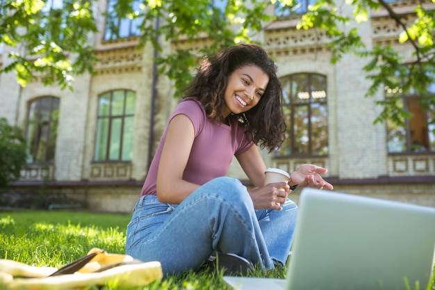 Styding nel parco. una donna dalla pelle scura seduta sull'erba e che studia