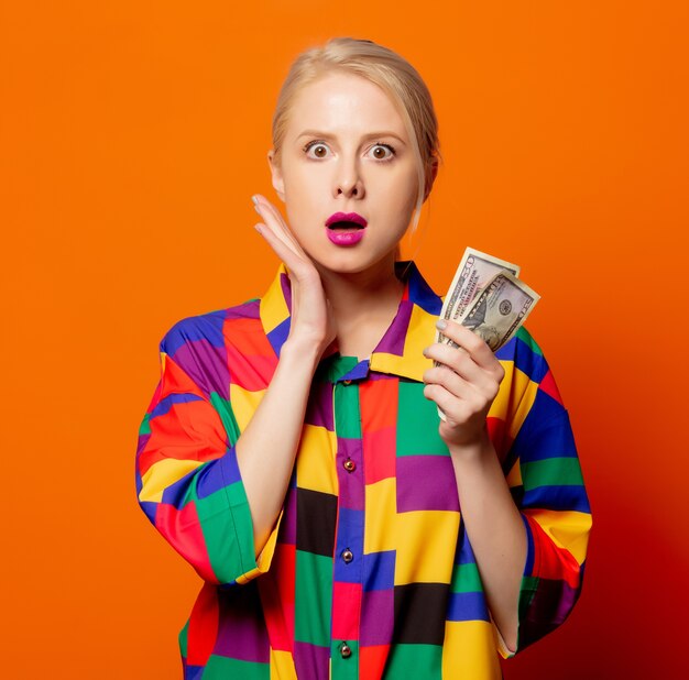 Style blonde in 90s clothes with dollars on orange