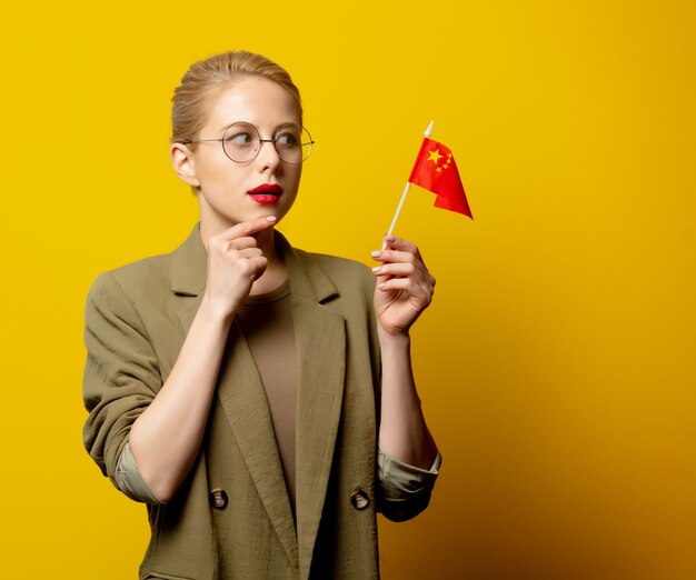 Style blonde woman in jacket with Chinese flag on yellow