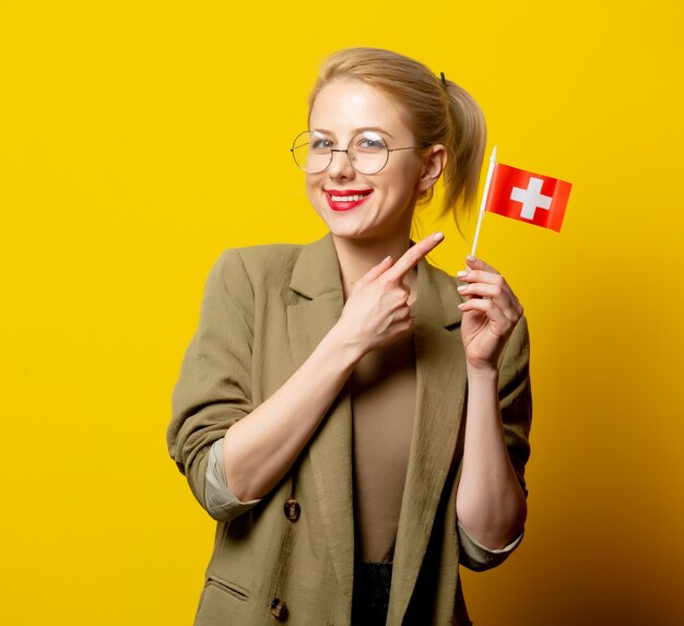 Style blonde woman in jacket with Swiss flag on yellow