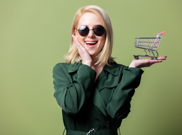 Style blonde woman in sunglasses with shopping cart