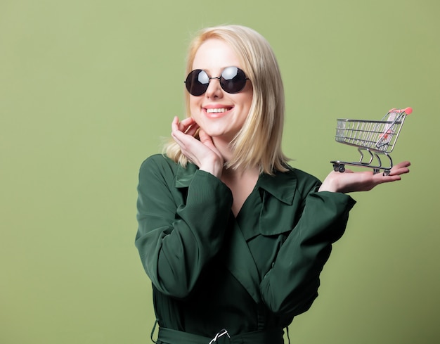 Style blonde woman in sunglasses with shopping cart