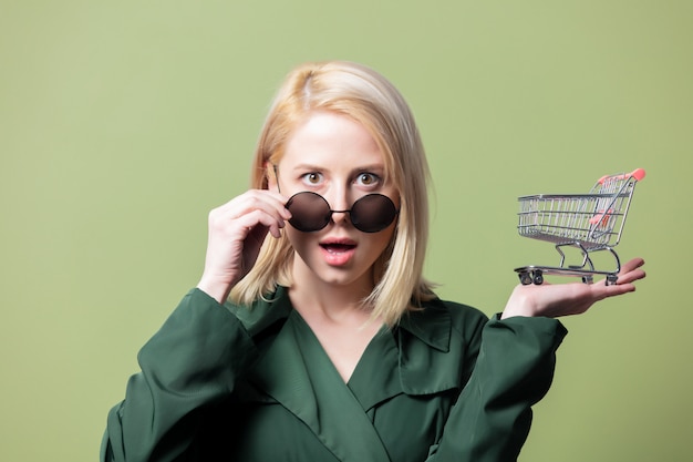 Style blonde woman in sunglasses with shopping cart