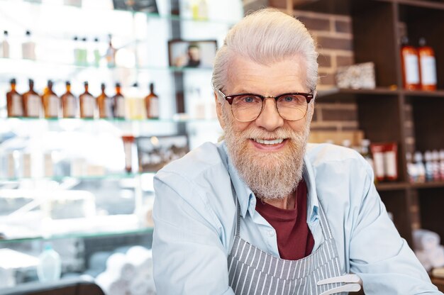 Photo on style. cheerful bearded man keeping smile on his face while looking straight at camera