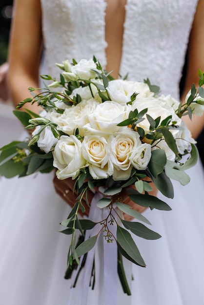 Style floral arranging wedding concept young woman dressed in extremely beautiful snowy white dress with puffy skirt is holding great bunch of different flowers stretched with yellow ribbons