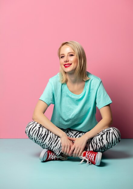 Style girl in zebra print clothes sitting on blue floor near a pink wall