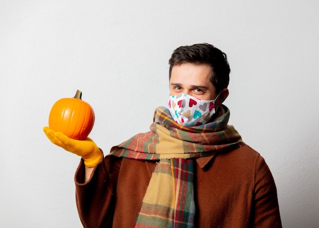 Style man in coat and scarf with pumpkin