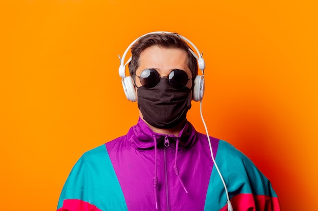 Style man in face mask and 80s tracksuit with headphones