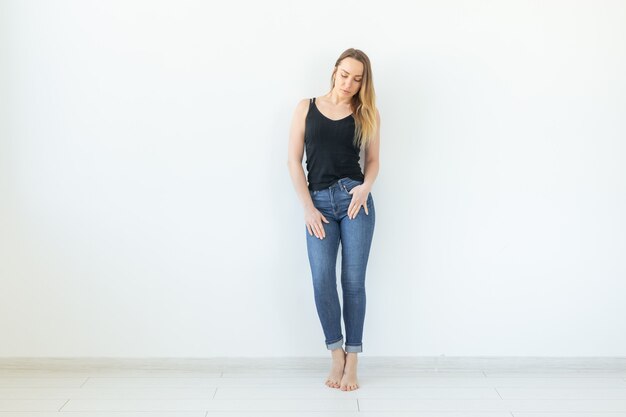 Stile, concetto di persone - giovane donna in jeans e camicia nera in piedi su sfondo bianco con