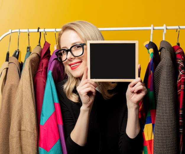 Style woman in black formal dress hold board next to clothes on\
rail hanger