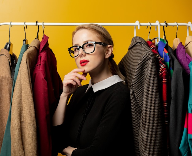 Style woman in black formal dress with clothes on rail hanger