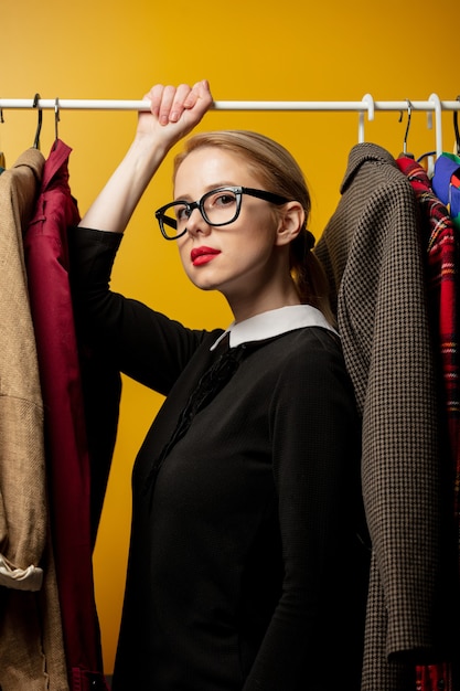 Style woman in black formal dress with clothes on rail hanger