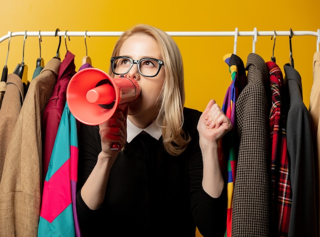 Foto stile donna in abito formale nero con megafono e vestiti su rotaia