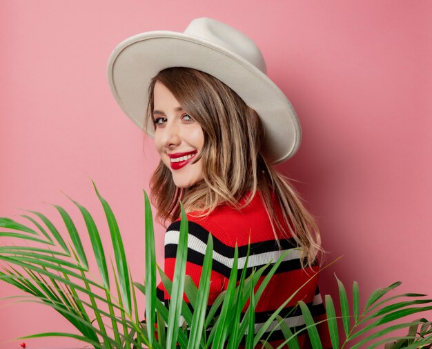 Style woman in striped sweater and hat on pink wall