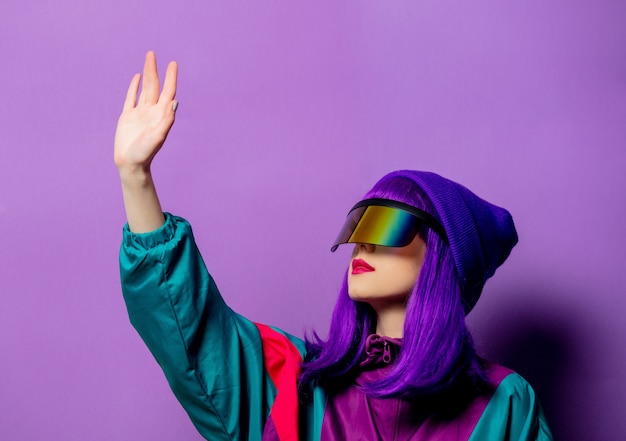 Style woman in VR glasses and 80s tracksuit on violet wall