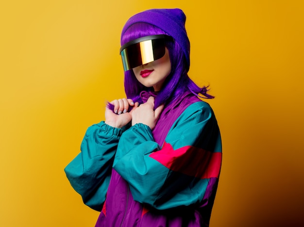 Style woman in VR glasses and 80s tracksuit on yellow wall