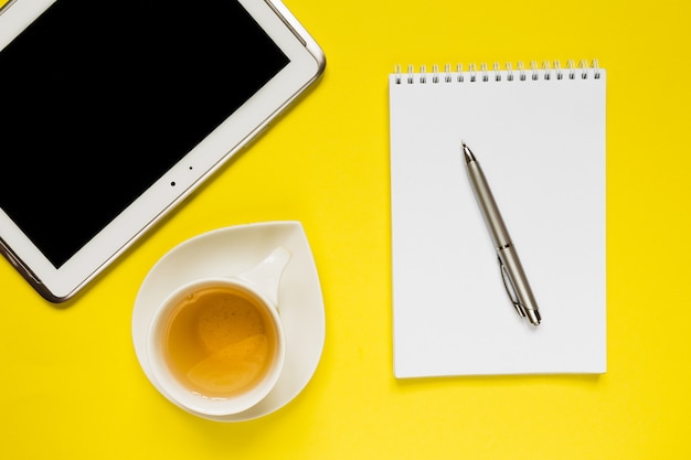 Styled  photography yellow office desk table with blank notebook, computer, supplies and tee cup. 