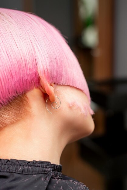 Styling en knippen van geverfd roze haar van jong model achteraanzicht in een kapsalon Roze kort kapsel