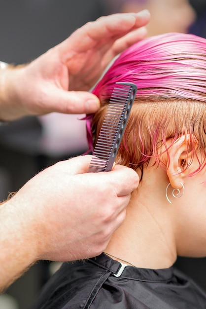 Styling female hair. Male hairdresser makes hairstyle for a young woman in a beauty salon.