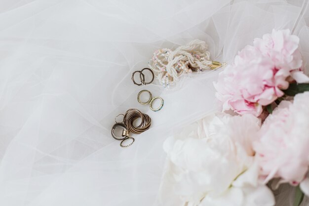 Stylish accessories on soft tulle fabric with peony bouquet Bridal morning Feminine essentials