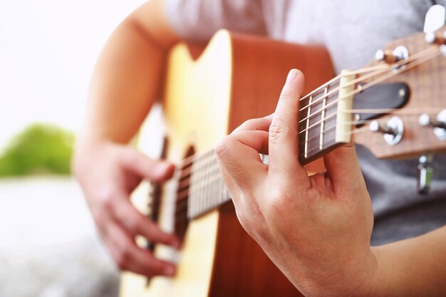 Stylish acoustic guitar playing by hand artist musician in public park