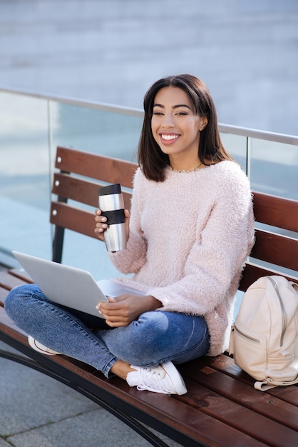 Stylish active gorgeous woman spending time outside and getting her work done while using her gadget