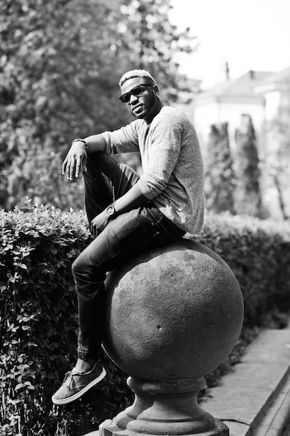 Foto elegante ragazzo afroamericano su maglione grigio e occhiali da sole neri in posa su strada ragazzo nero alla moda