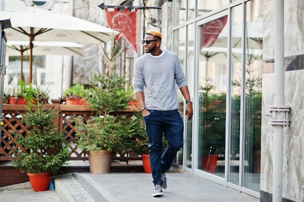 Stylish african american boy on gray sweater and black sunglasses posed at street Fashionable black guy