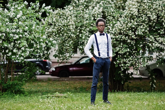 Stylish african american business man at pants with suspender
and shirt with bow tie hat and glasses posed outdoor