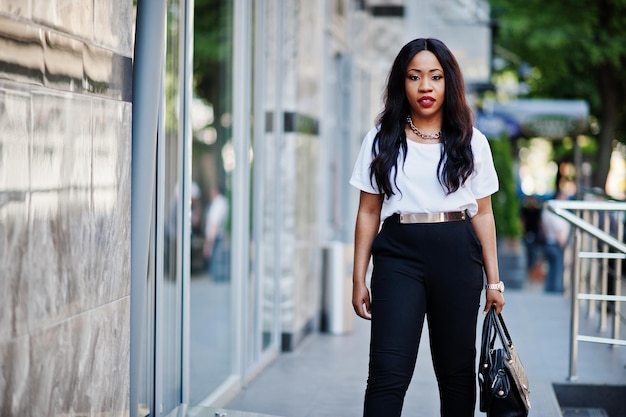 Stylish african american business woman with handbag on streets of city