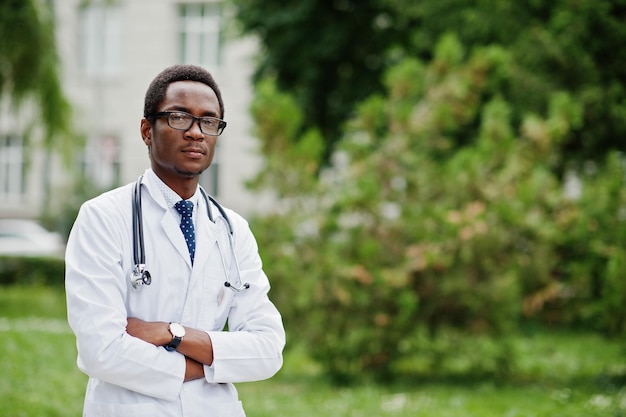 Elegante medico afroamericano con stetoscopio e camice da laboratorio con occhiali in posa all'aperto