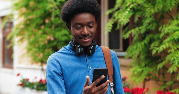 사진 걷는 동안 화상 통화를 위해 스마트폰을 사용하여 갈색 머리를 한 세련된 아프리카계 미국인 남자...