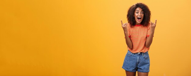 Stylish african american woman being delighted and excited before cool concert showing rock n roll person