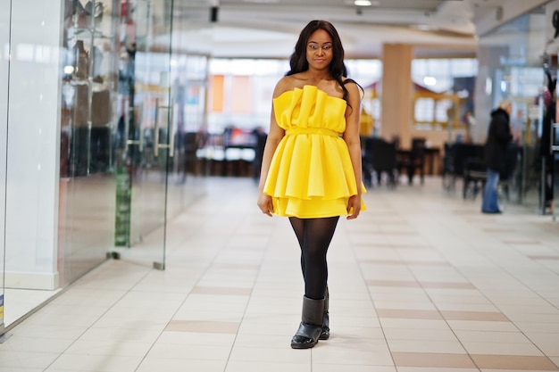 쇼핑몰에서 포즈를 취한 노란색 드레스를 입은 세련된 아프리카계 미국인 여성