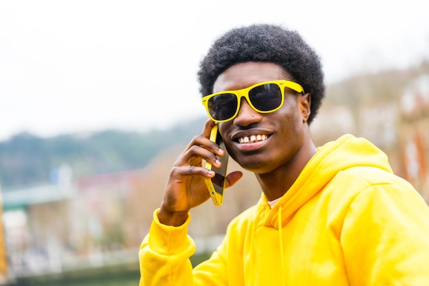 Stylish african man looking at camera while using phone