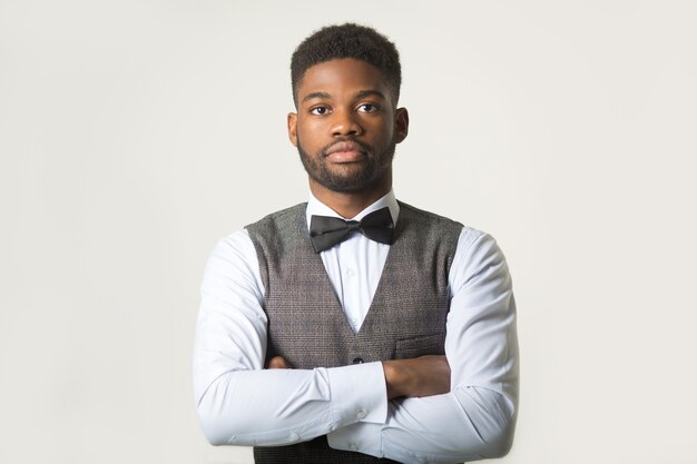 stylish african man in a waistcoat on a white wall