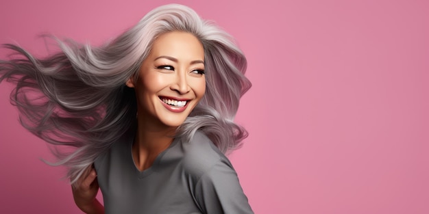 A stylish Asian woman with long hair on a pink background Luxurious middleaged woman with a long hair looking at copy space