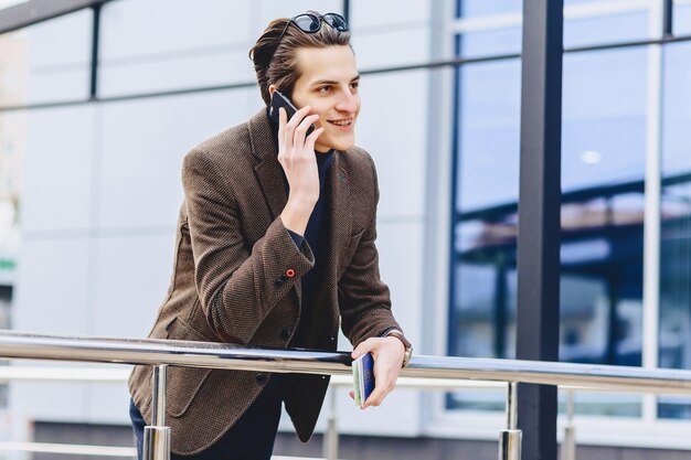 Stylish attractive guy in jacket with phone passport and tickets