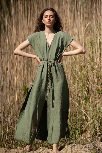 Foto donna sorridente esile attraente alla moda sulla spiaggia in vestito di tendenza della moda di stile estivo spensierato e felice