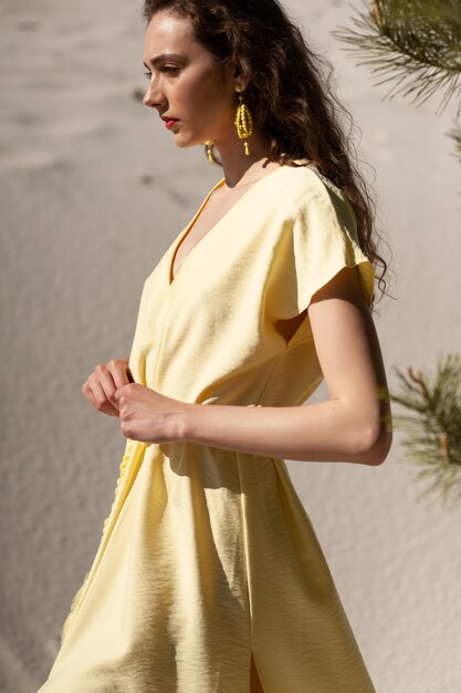 Foto donna sorridente esile attraente alla moda sulla spiaggia in vestito di tendenza di moda di stile di estate felice divertendosi