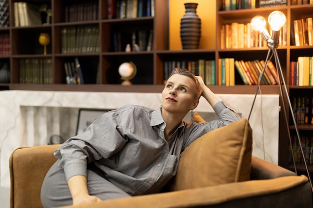 Stylish authentic caucasian mature woman with a short haircut sits glorified in an easy chair