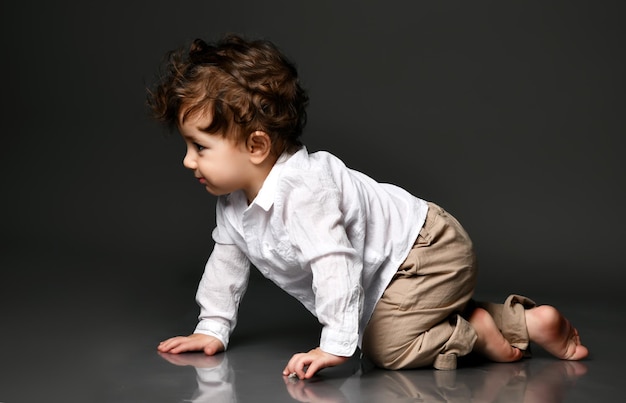 크롤링 하는 세련 된 아기 귀여운 맨발로 웃 고 웃 고 바지 셔츠를 입고 고립 된 초상화 회색 스튜디오 배경에 촬영 행복한 어린 시절 아이 성장과 발달 패션
