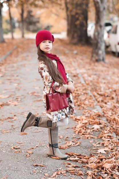 Stylish baby girl wearing trendy winter jacket walking in park Autumn season