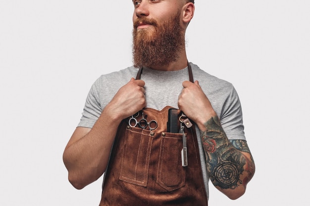 Stylish barber in apron looking away