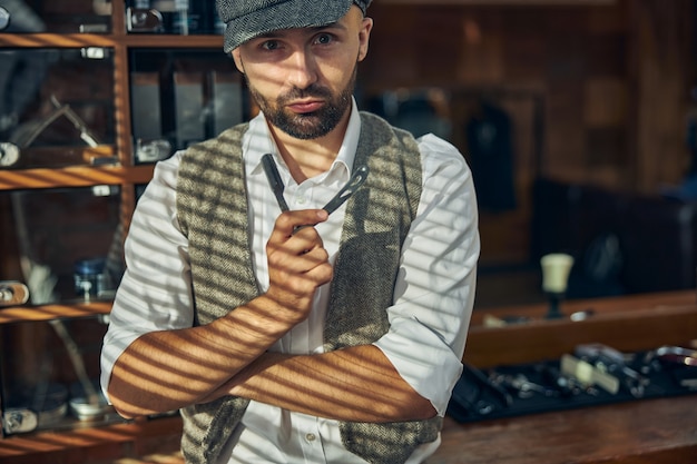 Stylish barbershop worker holding a cut-throat razor and looking at the camera