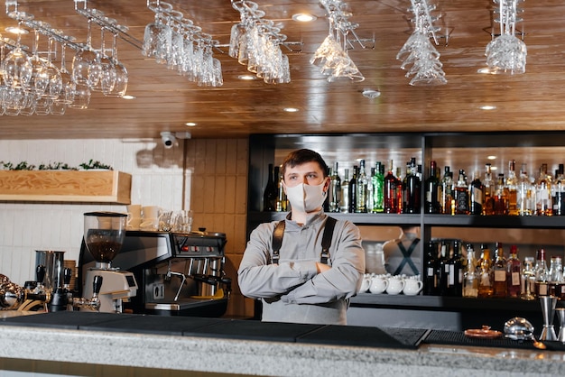 A stylish bartender in a mask and uniform stands near the bar during the pandemic The work of restaurants and cafes during the pandemic