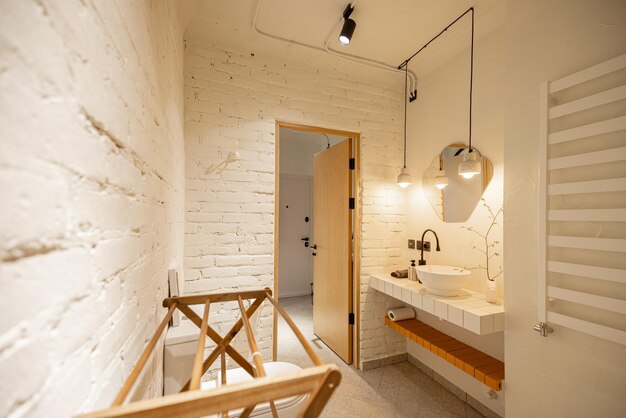 Stylish bathroom with brick walls painted in white