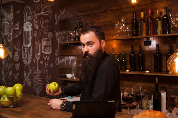 Elegante barista barbuto in una camicia sullo sfondo del bancone del bar. pub alla moda.