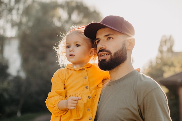 Stylish bearded father holding his little curly daughter