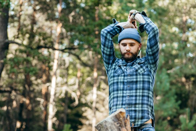 Stylish bearded forester chopping wood with an axe